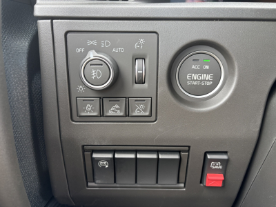 Volvo engine bay area controls panel showing headlight dial, engine start-stop button, and several auxiliary switches in a new Volvo VNL64T860 interior.