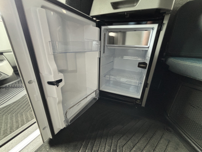 Open refrigerator/freezer unit inside a Volvo VNL64T860 truck cab showing empty shelves and door compartments.