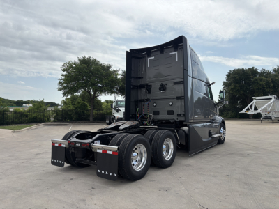 Volvo VNL64T860 truck tractor rear view showing triple rear axles and fifth wheel mount in sleeper cab configuration.