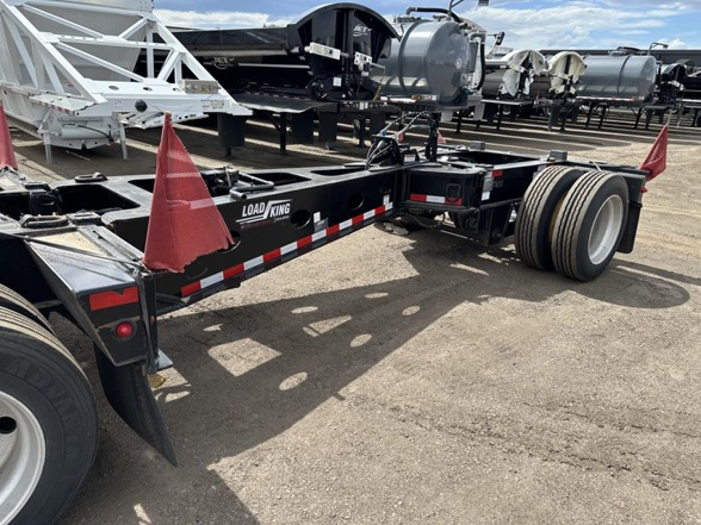 Load King Mech Stinger lowboy trailer shown from side rear angle with dual rear axles and black frame, Load King branding on rail.