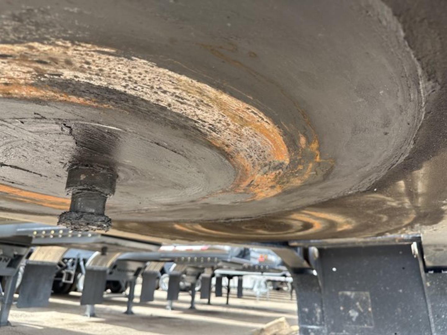 Low-angle view of a Load King Mech Stinger trailer underside showing a circular wear ring and mounting hardware with rust-like discoloration.