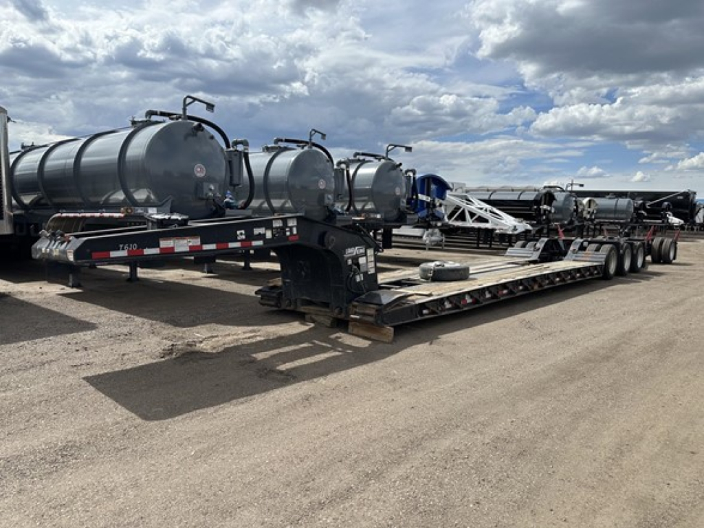 Trailer with multiple cylindrical tanks on a long lowboy chassis showing hydraulic ramps and tanker attachments.