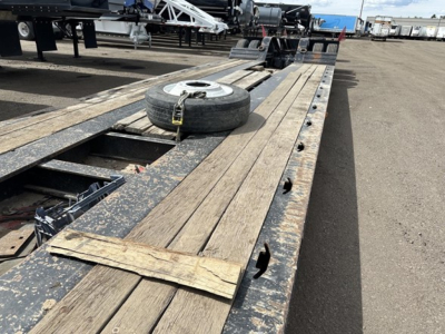 Load King mech Stinger lowboy trailer deck showing wooden boards and a spare tire mounted on the deck.