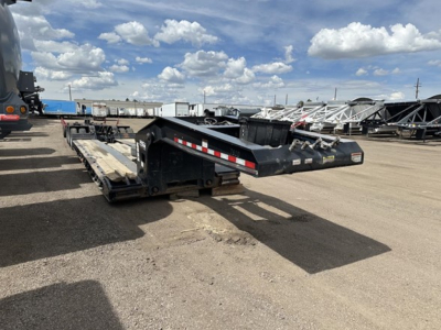 Loader trailer deck showing Load King Mech Stinger lowboy trailer with reflective stripes and support beams.