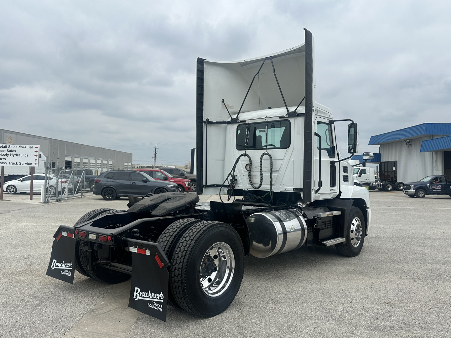 Truck rear view showing Mack AN42T chassis with raised dump trailer hitch, dual rear wheels, fuel tank, and back of sleeper cab. Visible elements include Bracken's dealership mudflaps with text.