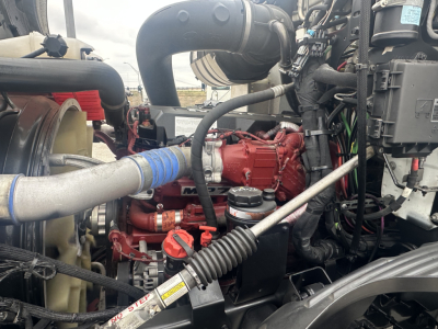 Mack AN42T engine bay showing red engine block, coolant hoses, intake pipe, and hydraulic lines.