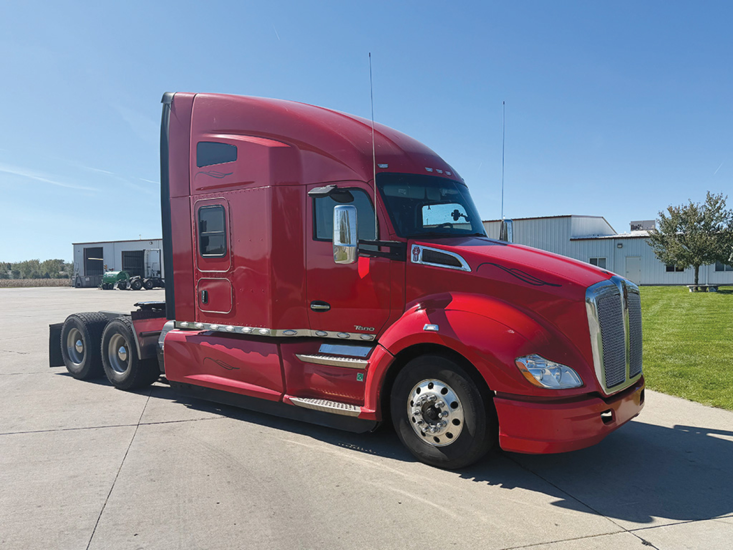Kenworth T680 tractor in red color, side view showing sleeper cab, front grille, and tandem rear axles.