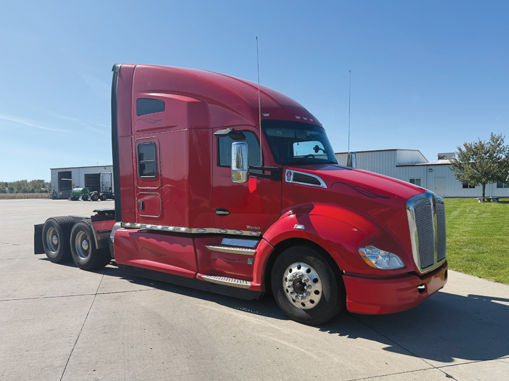 Kenworth T680 tractor in red color, side view showing sleeper cab, front grille, and tandem rear axles.