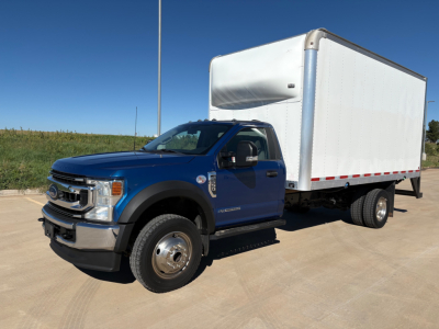 Ford F-550 box truck in blue cab with white box, side view, front grille and dual rear wheels visible.