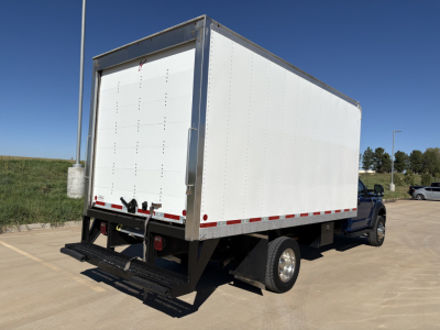 Box truck with cargo box rear and blue cab, Ford F-550, side view showing rear bumper and taillights, empty cargo area, clear weather.