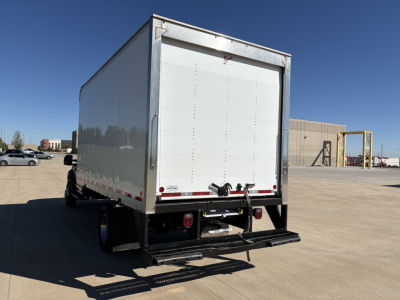 Ford F-550 box truck rear view showing cargo area and rear bumper with step. Clear sky and parking lot surroundings.