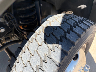 Ford F-550 front wheel well showing off-road style tread tire and suspension components.