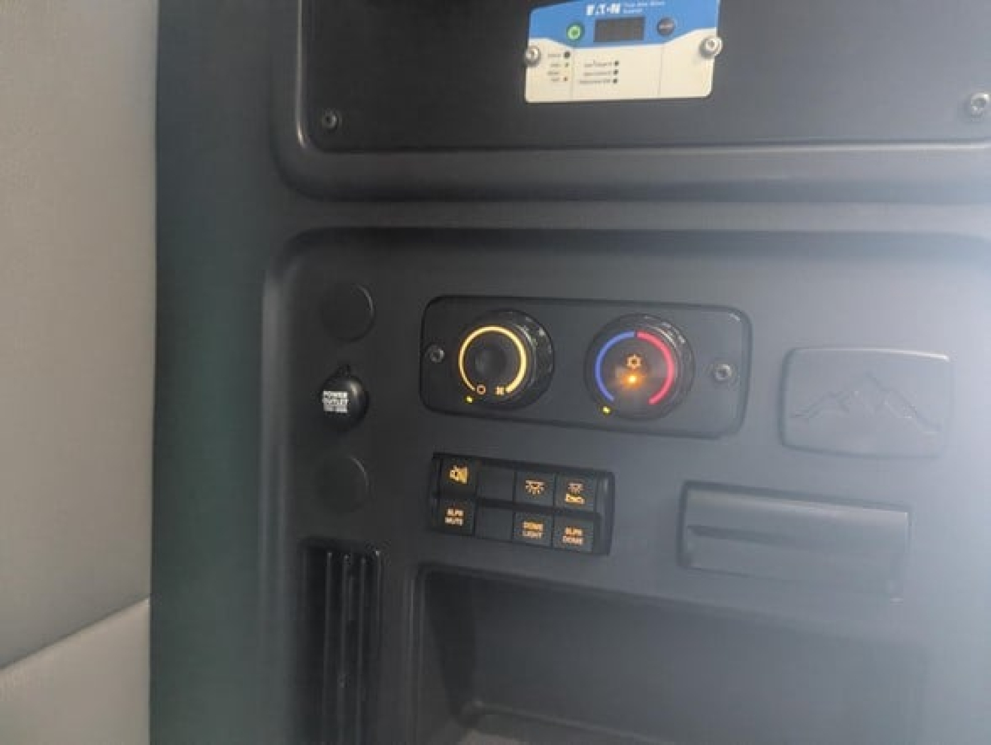 Dashboard controls inside Freightliner Cascadia 126 cab with circular climate knobs and small switches.