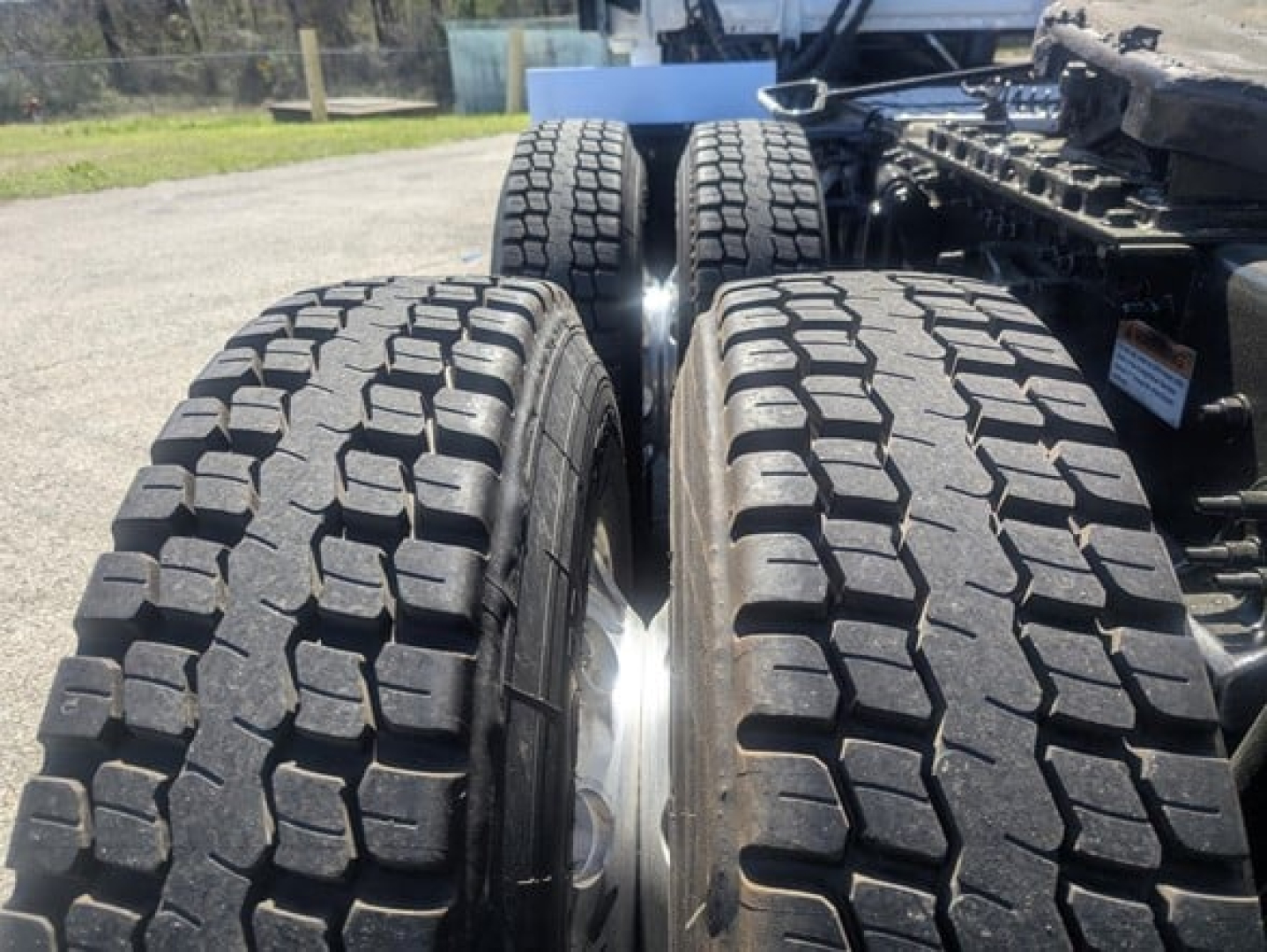 Truck rear dual tires on Freightliner Cascadia chassis showing heavy tread blocks and wheel rims.