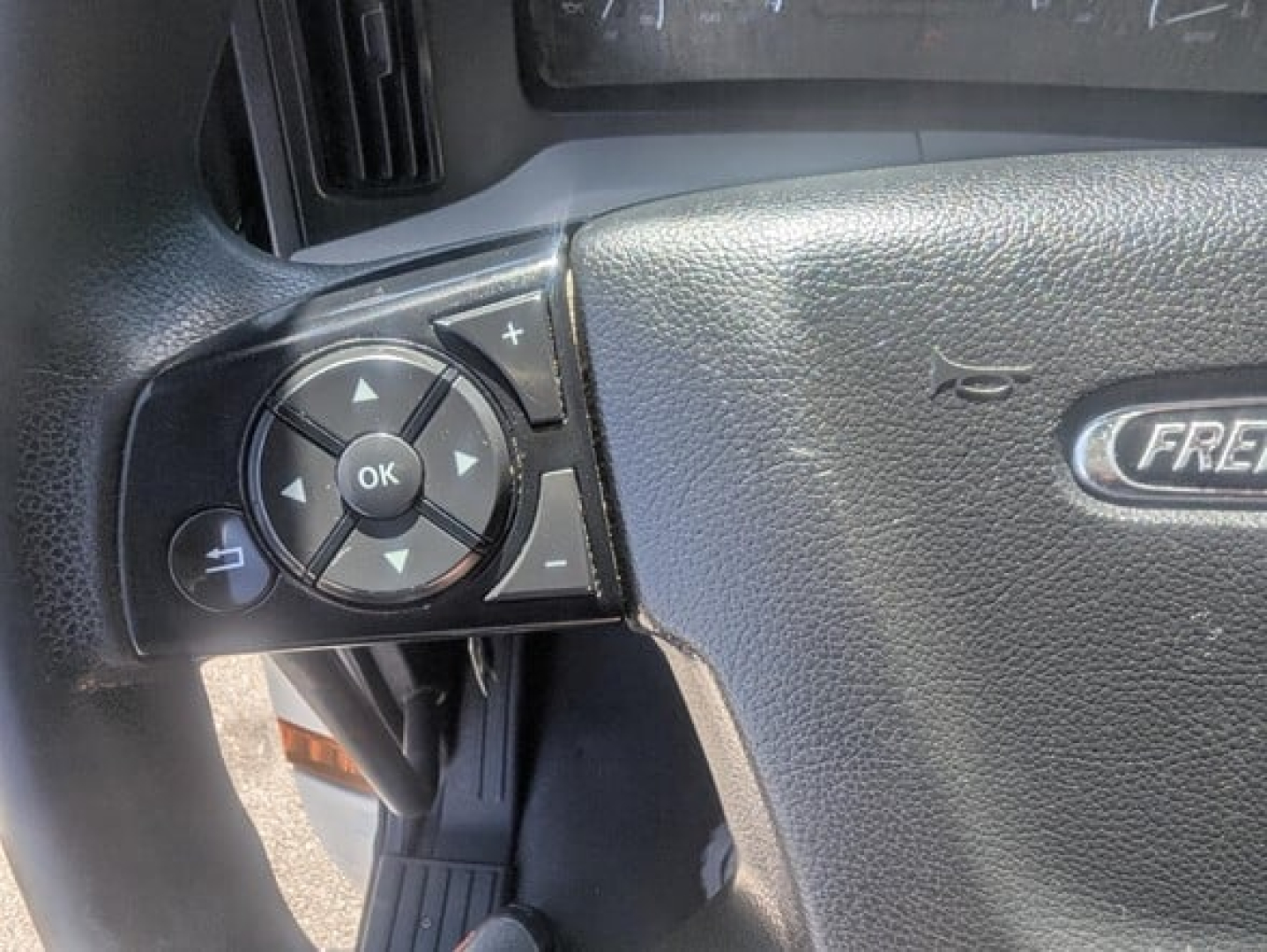 Freightliner Cascadia steering wheel controls with OK button and directional pad visible