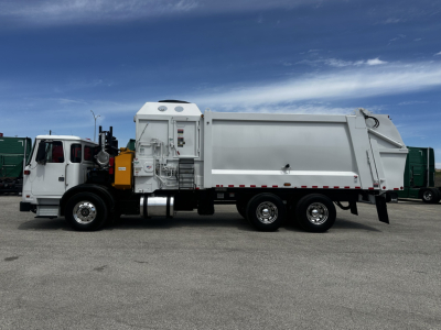Autocar XPEDITOR yard truck side view showing large dump body and cab with white exterior, diesel engine compartment, and dual rear axles.