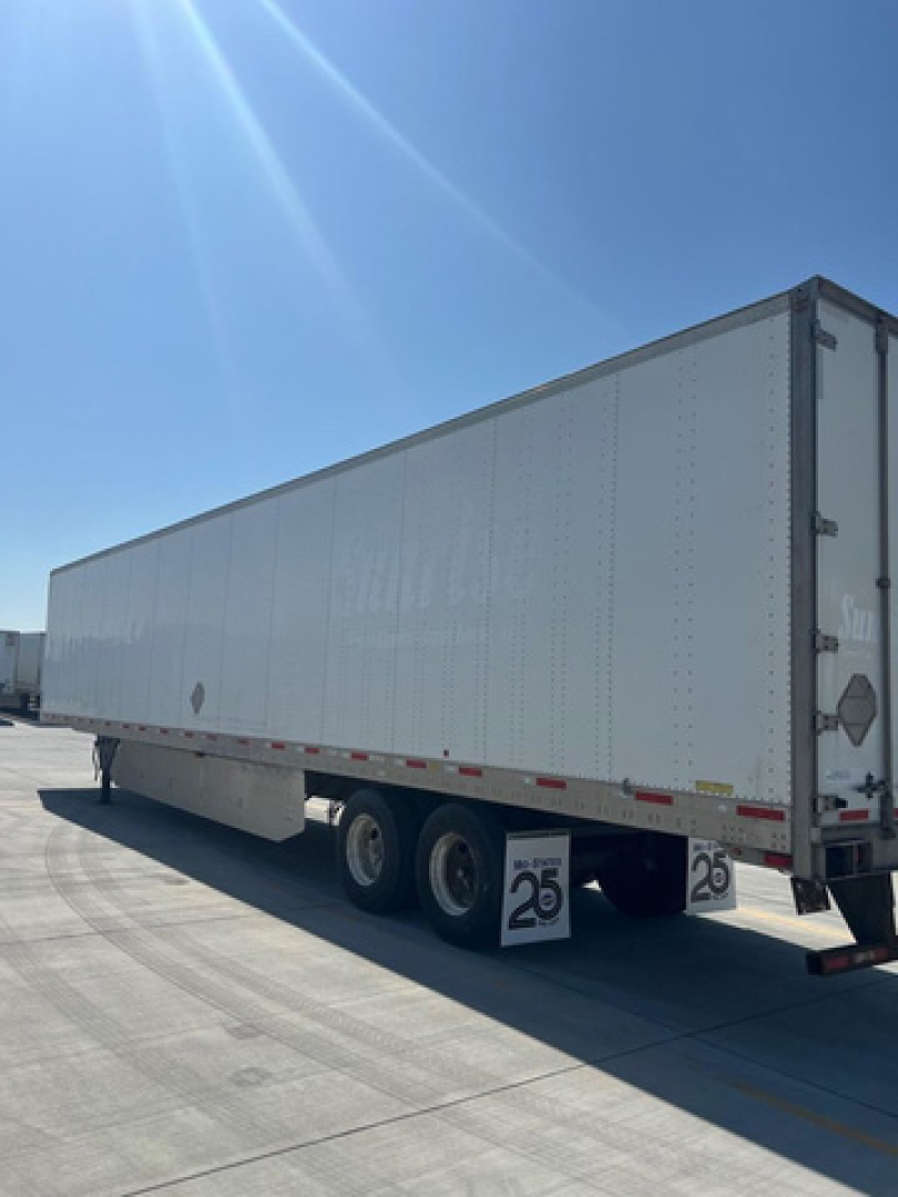 Trailer side view showing a white utility van trailer with dual rear axles and a 25 mph sign near the wheels.