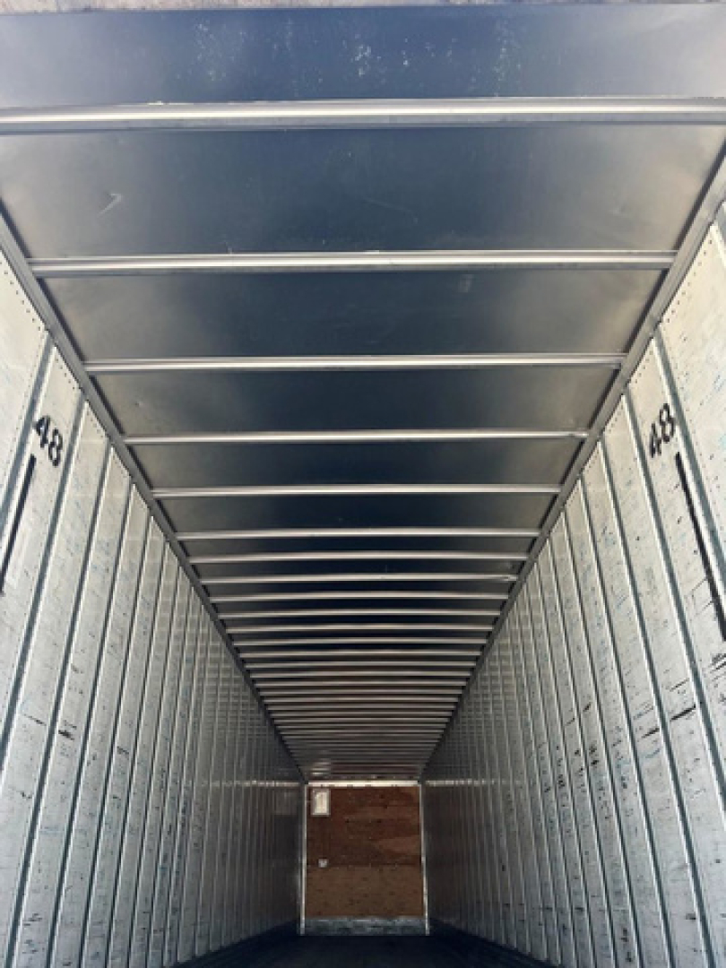 Trailer interior showing metal walls and ceiling with 449 markings along sides and a wooden rear door.
