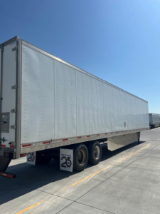 Semi-trailer van with a silver corrugated aluminum exterior, side view showing triple rear axles and mudflaps with 25 decals; VIN 1UYVS2538EP818204 visible on listing.