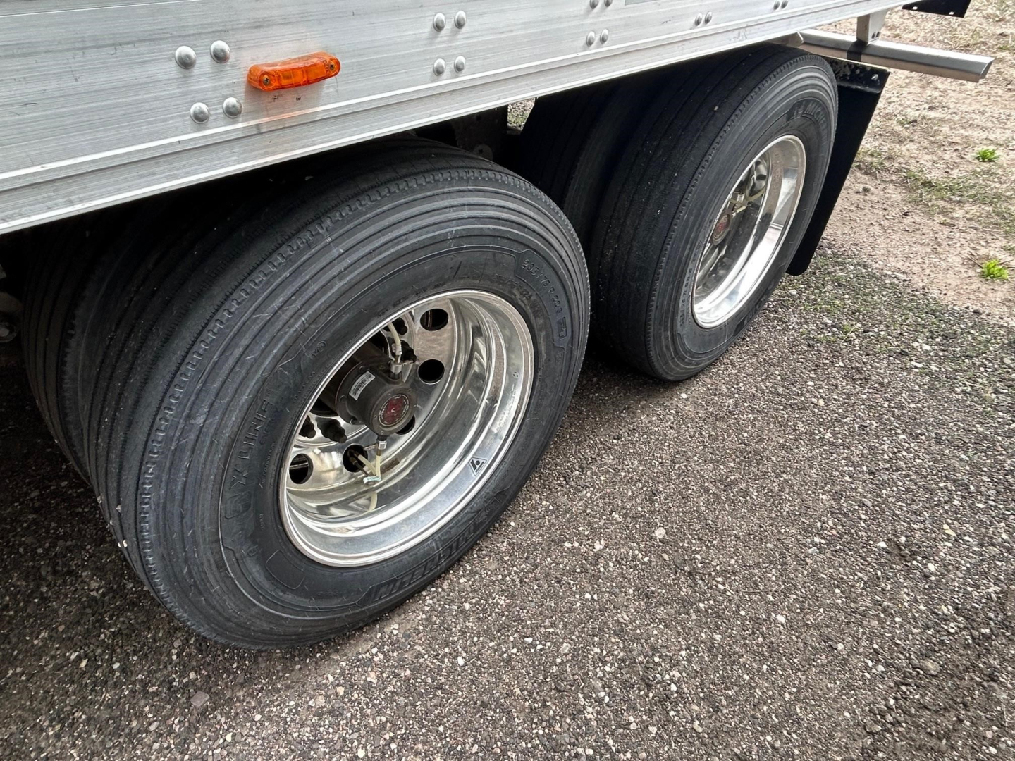 Trailer dual rear wheels on a Utility 3000R reefer trailer showing aluminum side panel and chrome rims.