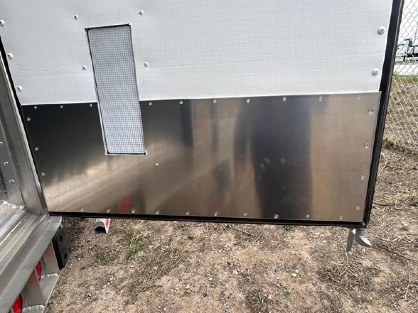 Trailer rear lower panel of a 2026 Utility 3000R trailer with a vertical rectangular vent and riveted metal surfaces.
