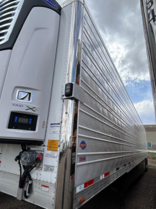 Utility 3000R trailer side and front showing Y8000-X refrigeration unit, latching doors, aluminum side panels, and safety decals.