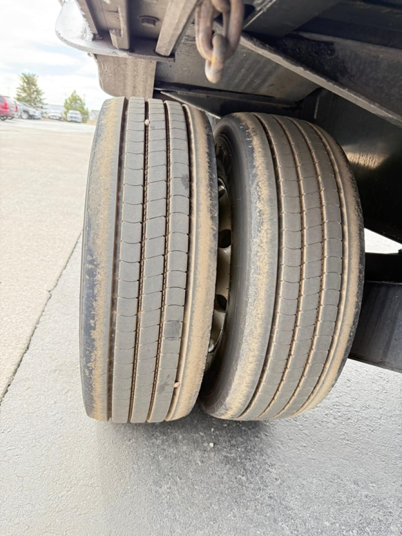 Dual tandem axle on a drop deck trailer with visible tires and suspension components.