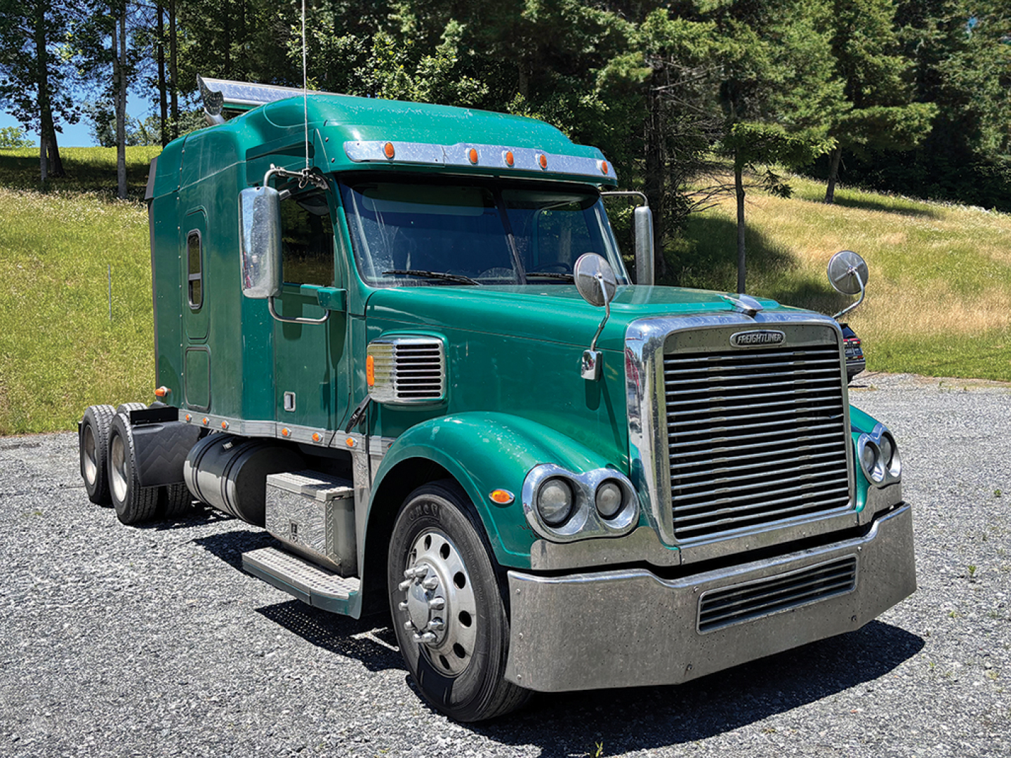Truck image showing a green Freightliner Coronado conventional sleeper truck with chrome grille, hood, and side mirrors.