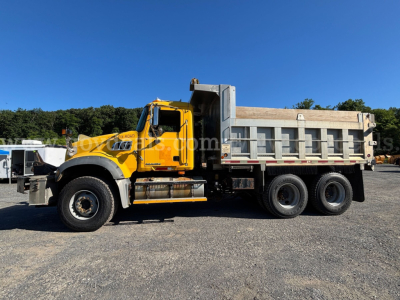 Dump truck body with a yellow Mack GU713 cab and gray dump bed, side view showcasing dual rear axles and heavy-duty tires.