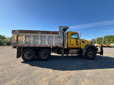 Truck side view of a yellow and white Mack GU713 dump truck with a large aluminum dump bed, dual rear axles, and black tires.