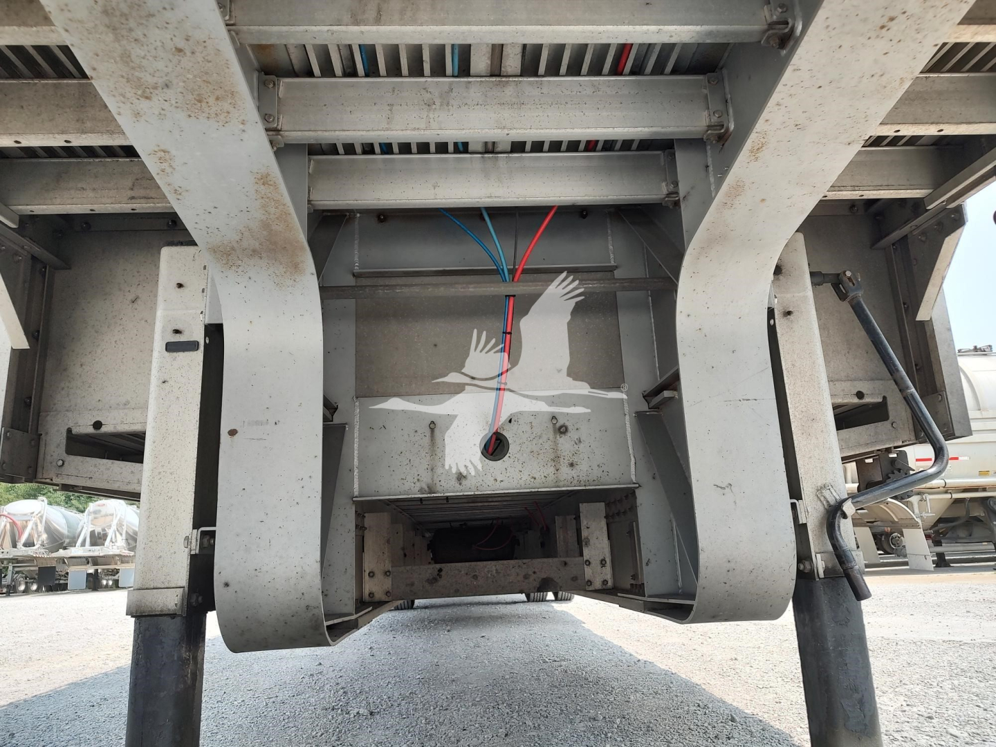 Trailer undercarriage showing hydraulic lines and frame of a 2018 Reitnouer Dropmiser drop deck trailer. Visible wiring, metal beams, and support legs.