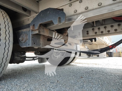 Drop deck trailer underside showing suspension, frame rails, wiring harness, and wheel; 2018 Reitnouer Dropmiser with visible components and riveted steel structure.