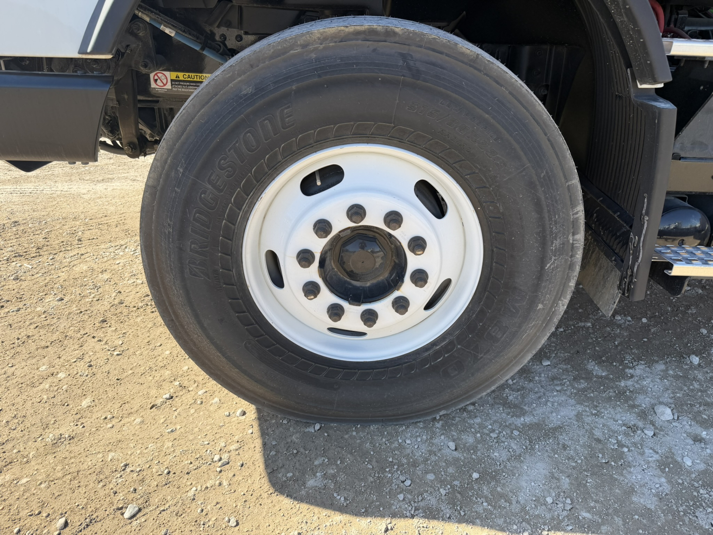 Volvo VHD86B300 truck wheel and fender with Bridgestone tire, white rim, visible side of cab chassis.