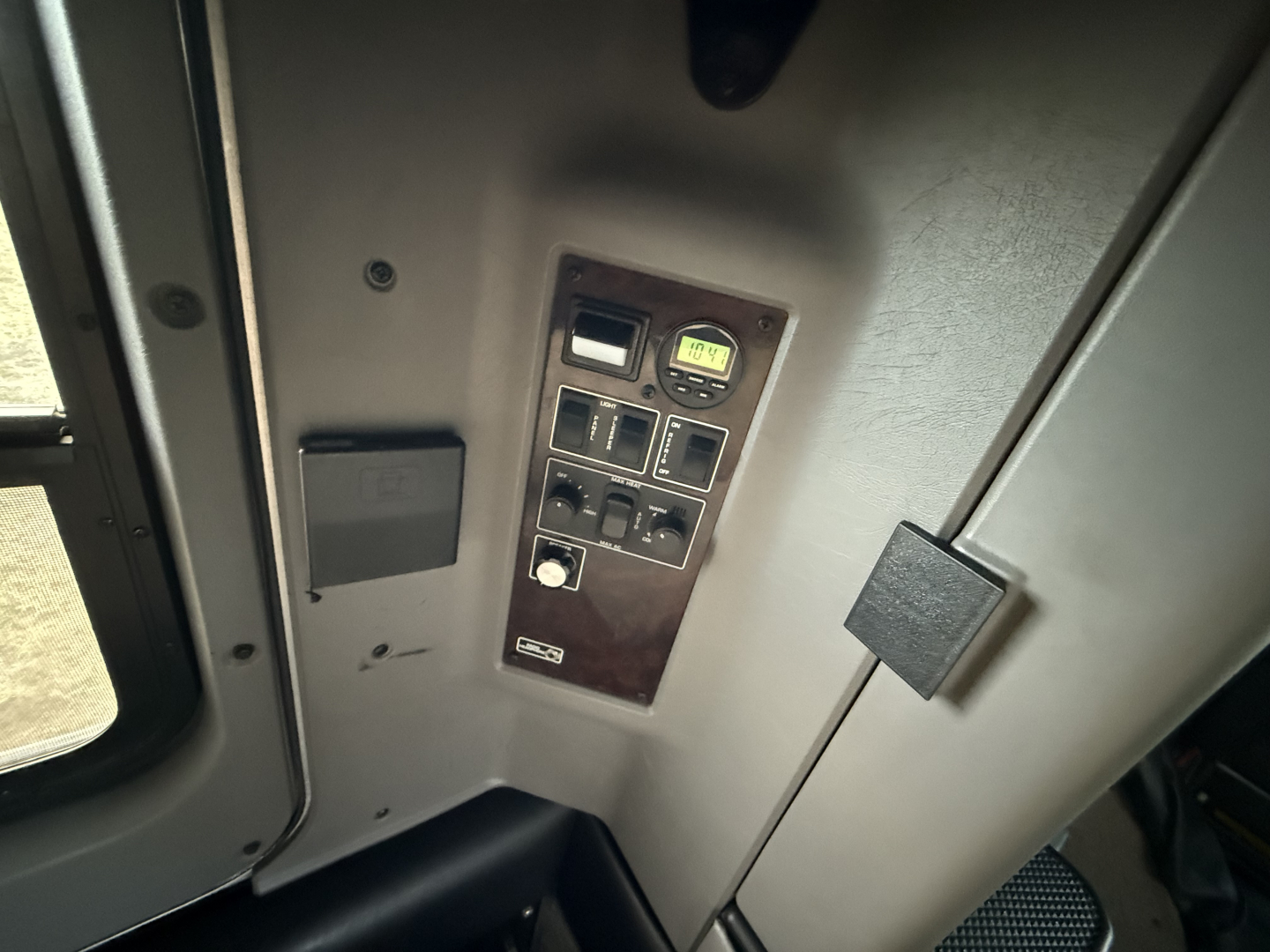 Kenworth W900L interior panel with control switches and gauge area showing switches and a small circular gauge.