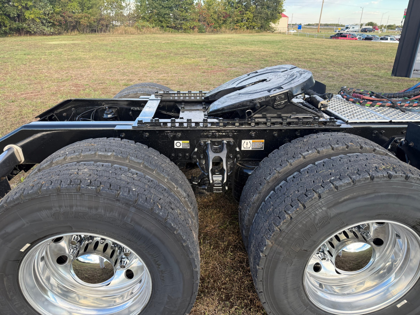 Kenworth W900L rear chassis showing dual rear axles and fuel/air lines with visible fifth wheel platform and suspension components.