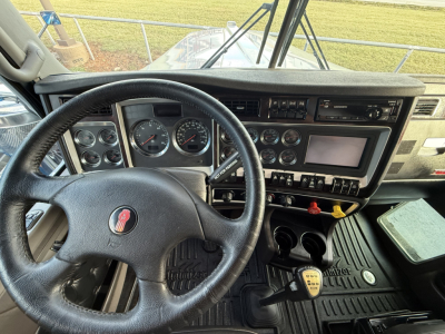 Kenworth W900L cabin dashboard and steering wheel showing multiple gauges and controls.