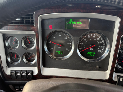 Dashboard of a Kenworth W900L truck showing multiple gauges and a small digital display reading 'Trip Info.'