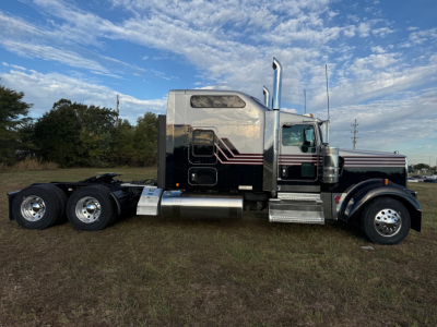 Kenworth W900L conventional sleeper truck side view showing chrome fuel tanks and dual rear axles, black and silver paint with burgundy and white pinstriping.