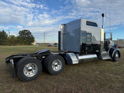 Kenworth W900L tractor conv sleeper truck side view showing dual rear axles, chrome fuel tanks, and silver aerodynamic sleeper cab with black stripe accents.