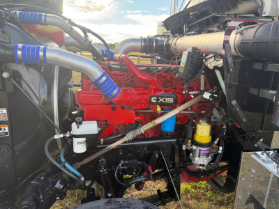 Kenworth W900L engine bay showing red XPDI-X15 engine with blue silicone hoses, fuel filter, and ancillary components in a used truck.