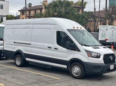 Ford Transit 350 HD cargo van in white, side view with raised roof, black bumper, and dual rear wheels. VIN partially visible on plate, parked in lot.