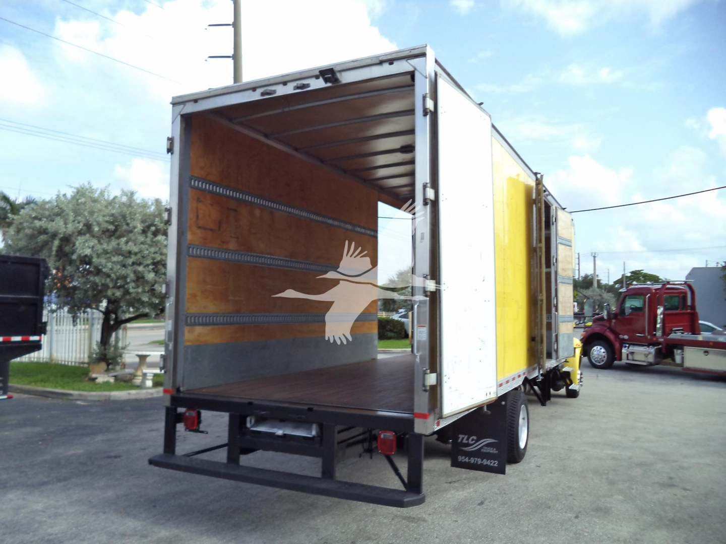 Truck cargo area of a 2020 International MV moving van showing empty cargo space with wooden side walls and rear doors open.