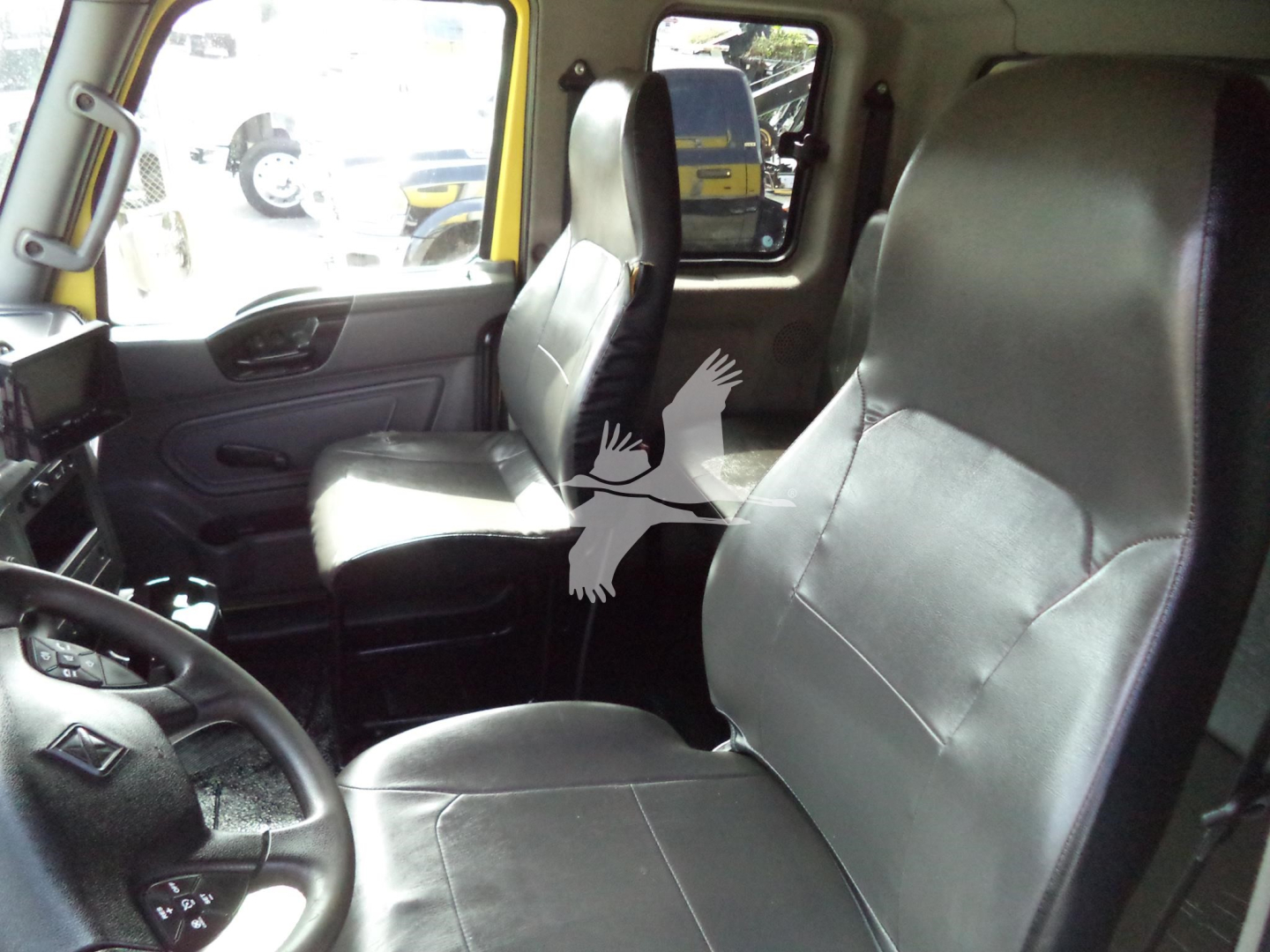 Interior of a 2020 International MV cab showing two black leather seats and steering wheel.