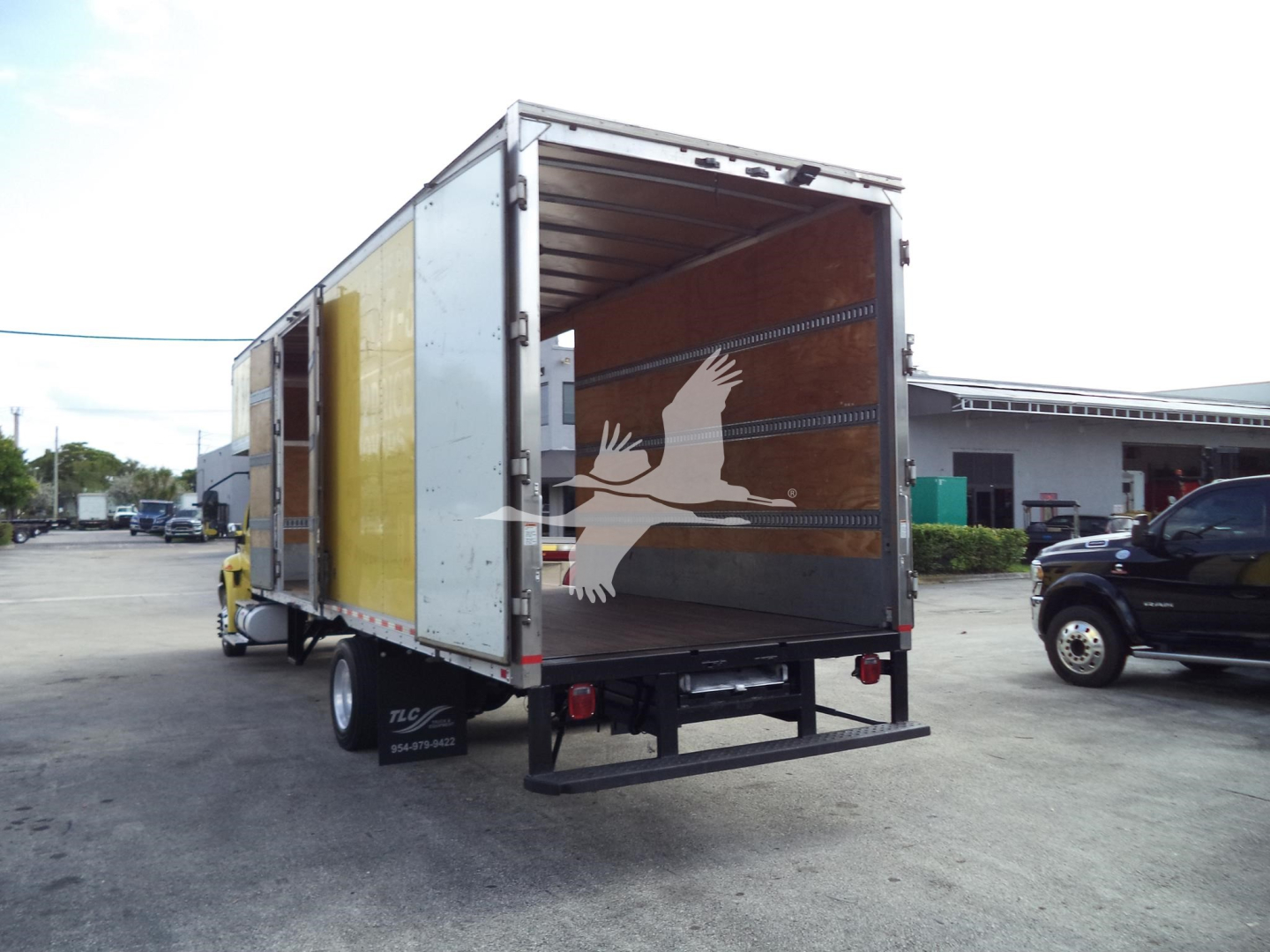 Box truck with open cargo area showing interior walls and loading ramp, rear view, International MV 2020 moving van.