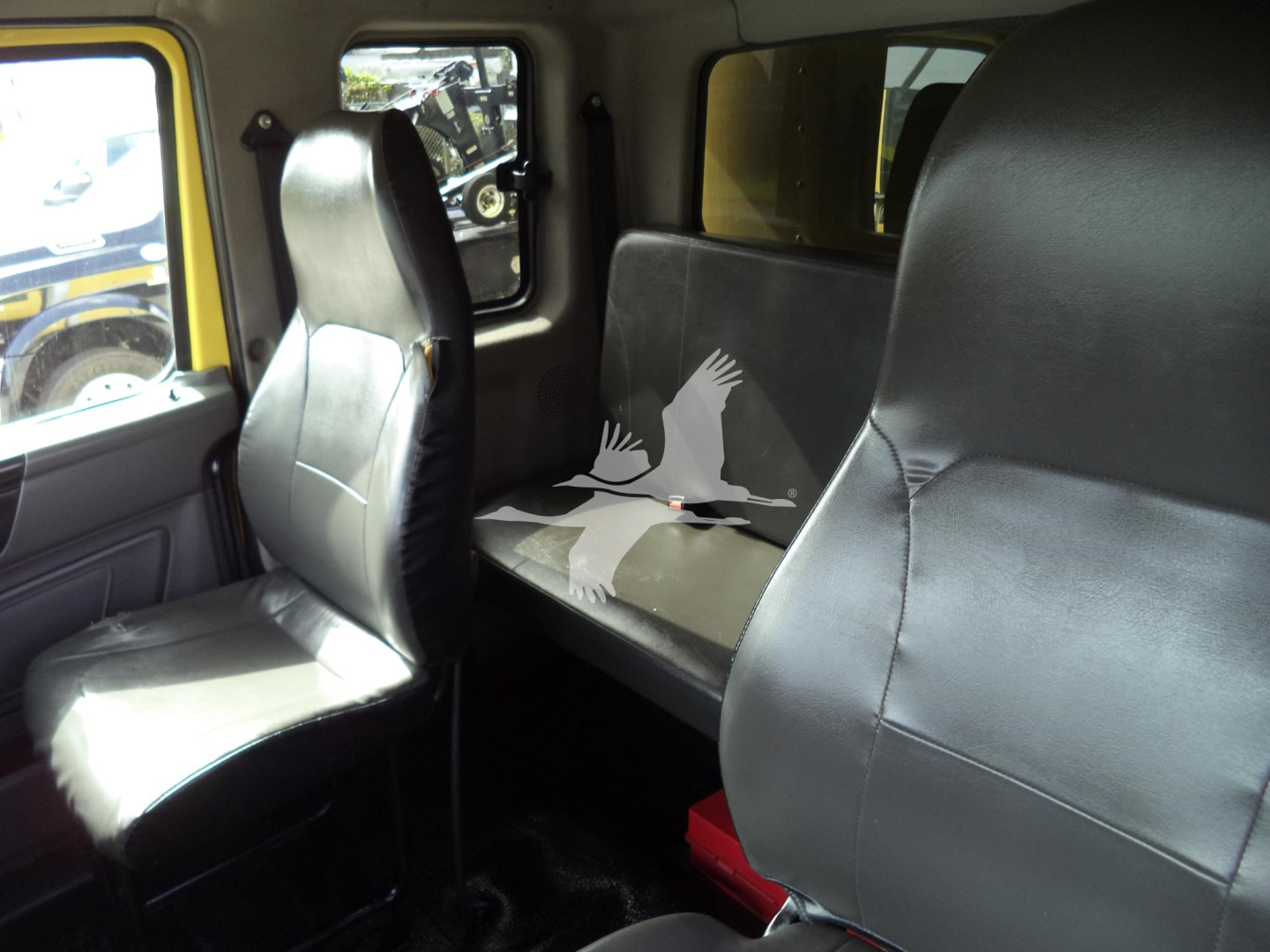 Interior of a 2020 International MV moving truck showing front passenger seat and rear bench seat with black upholstery.