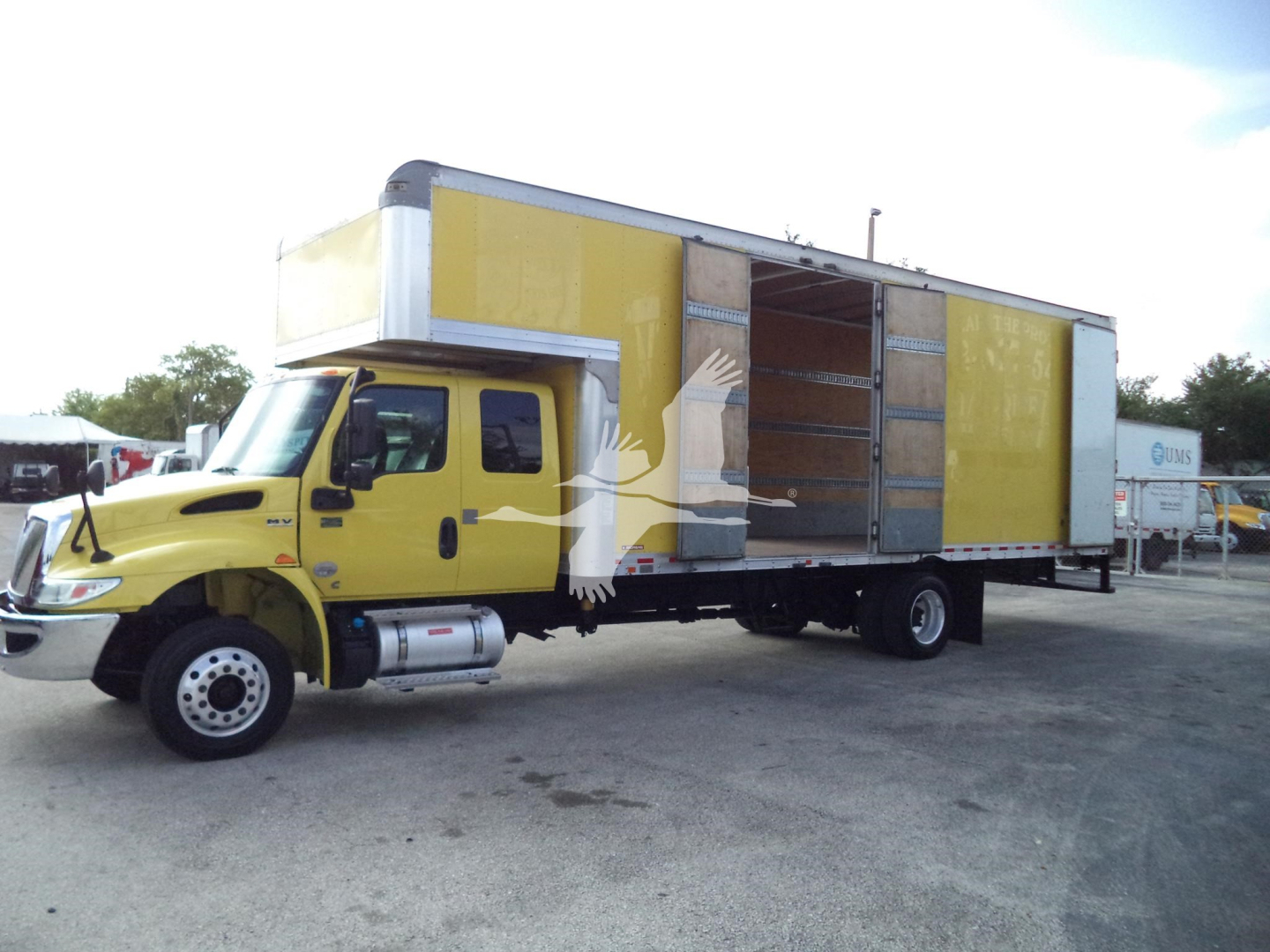 Truck box truck side view showing a yellow cab and a large amber moving box with open rear doors.