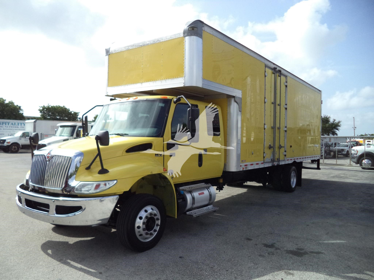 Truck cab and yellow box trailer in a parking lot, International MV moving van.