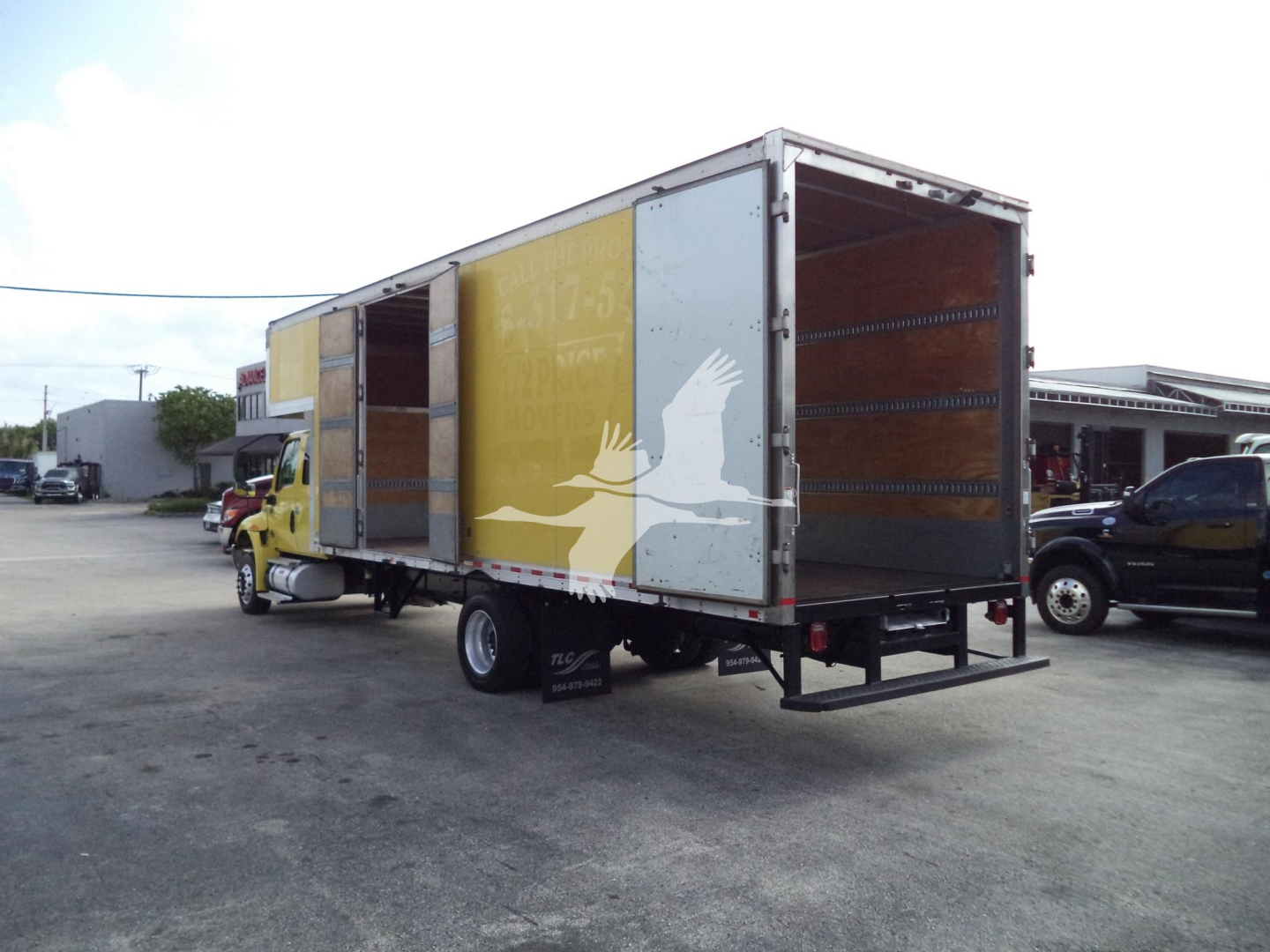 Truck with a large box trailer, rear and side view showing loading doors and interior walls. Visible text on the trailer includes faded graphics and possible branding, no legible model details.