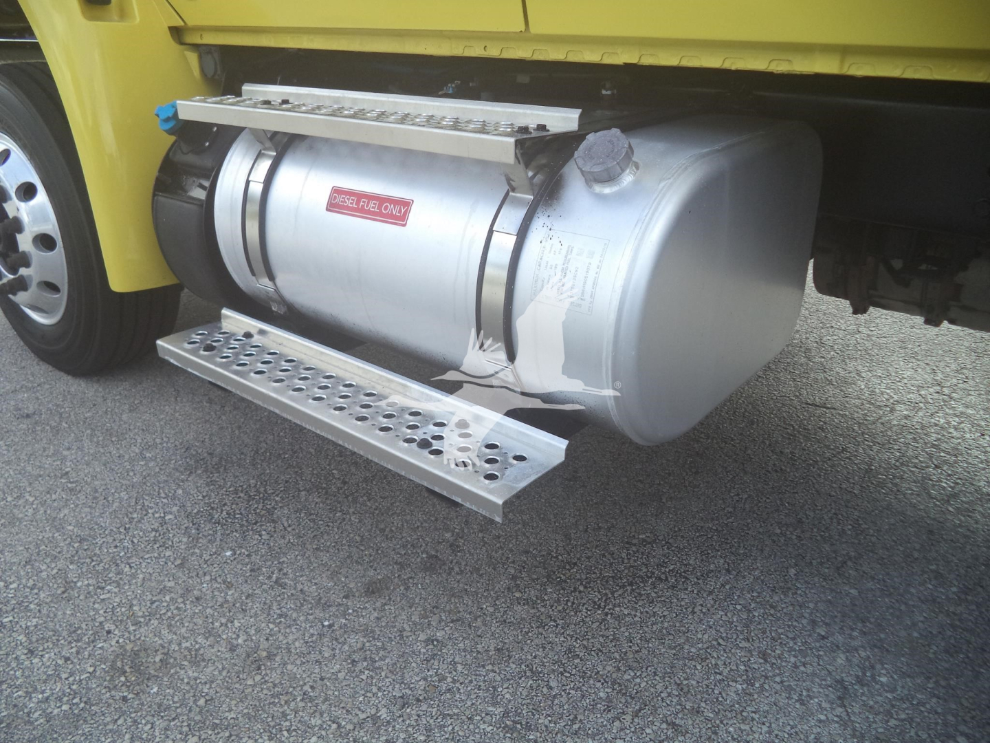 Tank underbody view on a 2020 International MV truck showing horizontal cylindrical fuel or air tank with a platform step and mounting straps.
