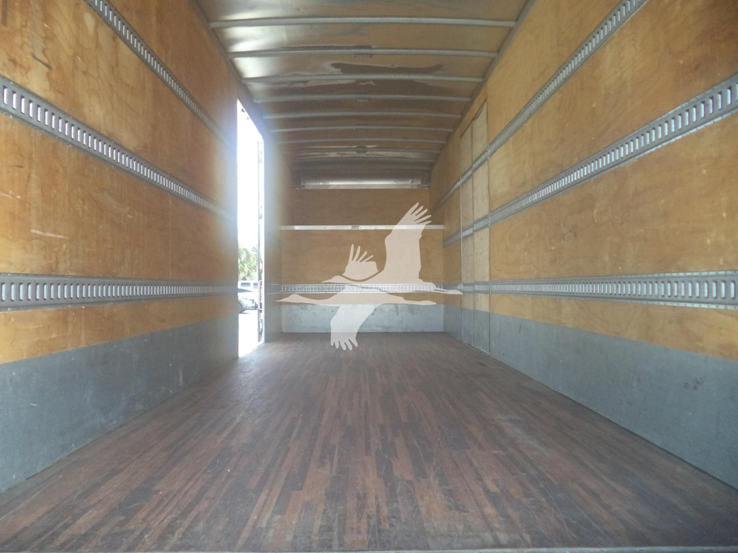Trailer interior showing wooden floor and metal side rails; faint white image of hands reaching with a circle near the far end.